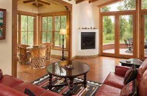 Large living room with leather couch, double doors to the outside patio, and natural light